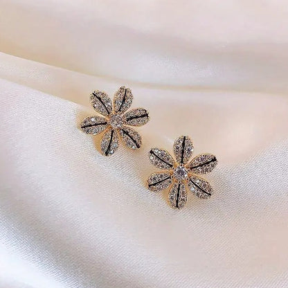 Black & Gold Rhinestone Flower Earrings with sparkling stones on a soft fabric background