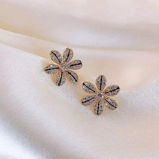 Black & Gold Rhinestone Flower Earrings with sparkling stones on a soft fabric background