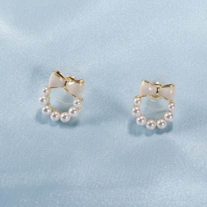 Pair of Ivory Bow Pearl Wreath Earrings on a light blue background