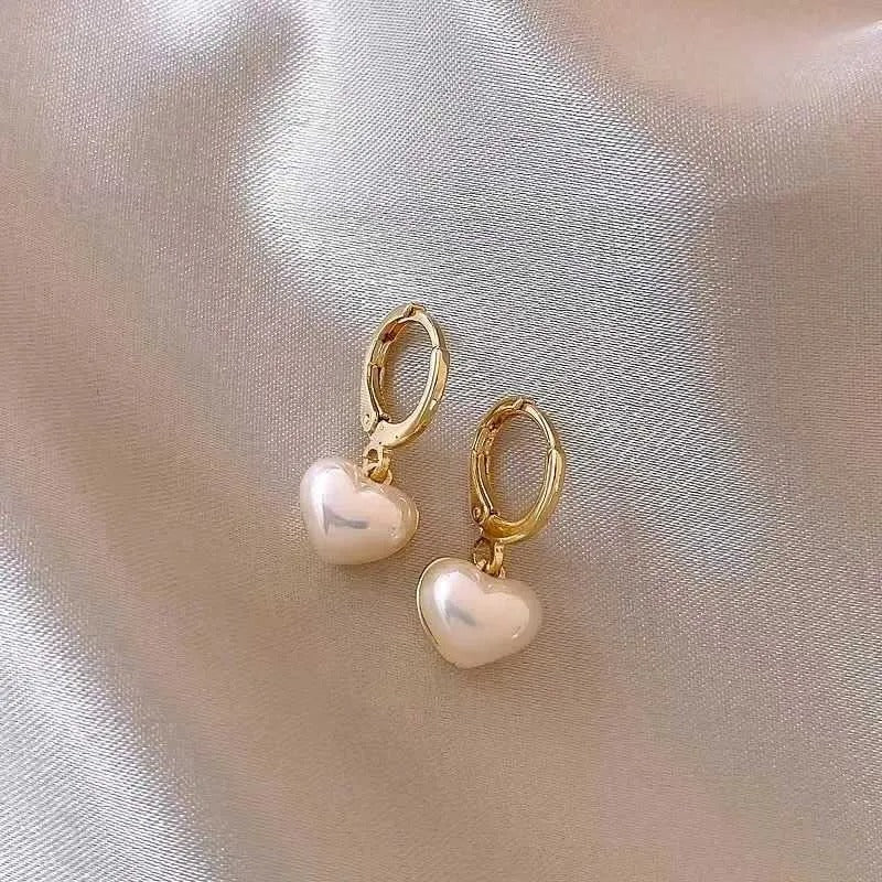 Iridescent Heart Drop Earrings with gold hoops on a soft fabric background