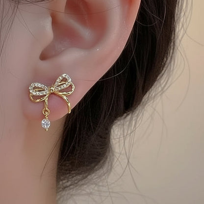 Sparkling Gold Crystal Bow Earrings with a small gemstone worn on an ear.