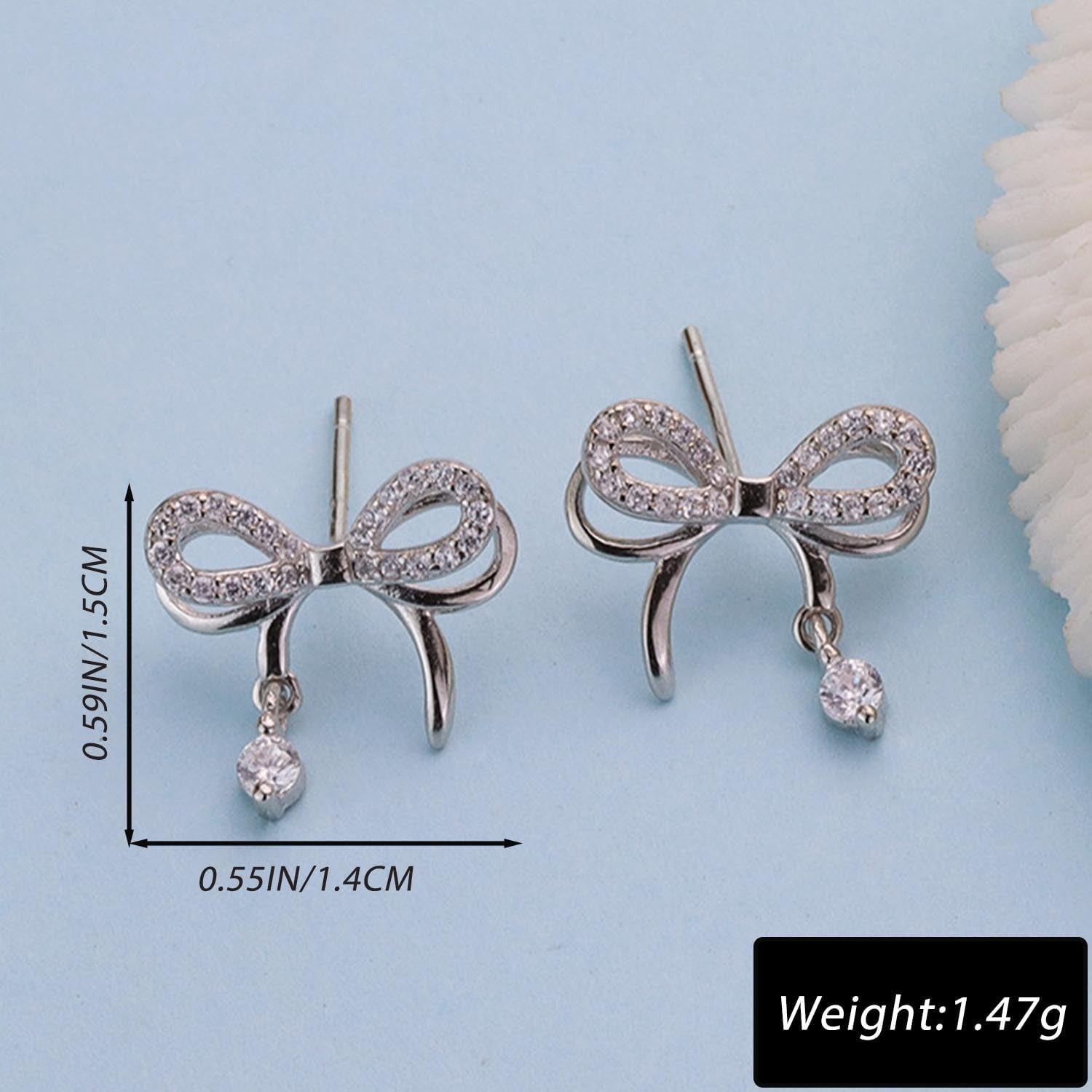 Silver Bow Earrings with small droplets on a light blue background with measurements and weight information.