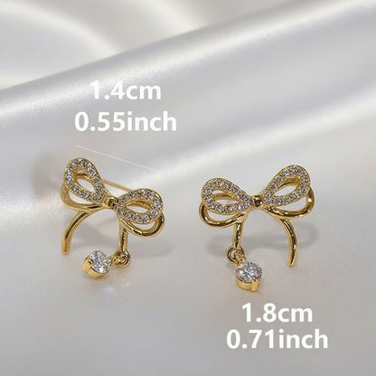 Sparkling Gold Crystal Bow Earrings with measurements on a reflective surface