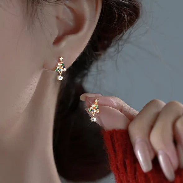 Close-up of a person wearing a Twinkling Christmas Tree Earring with red sweater