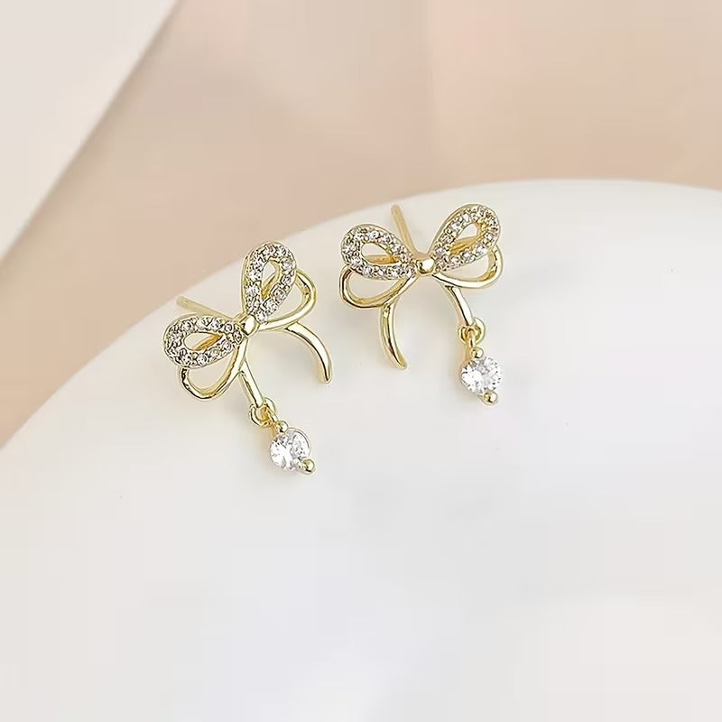 Sparkling Gold Crystal Bow Earrings with small crystals on a white surface