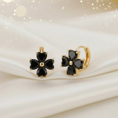 Pair of gold and black flower-shaped earrings on a white background