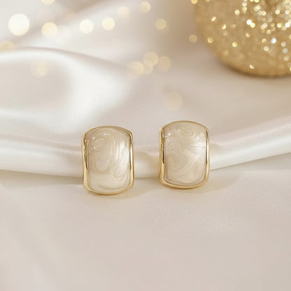 Gold-Trim Mother-of-Pearl Earrings on a white surface with a soft, blurred background