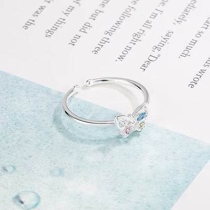 Pastel Butterfly Adjustable Ring on a light blue fabric background