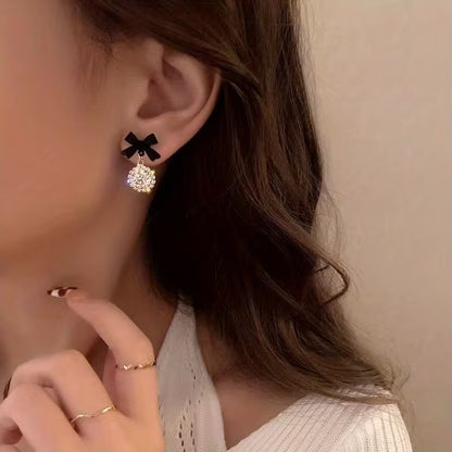 Close-up of a woman wearing a Black Bow Crystal Drop Earring