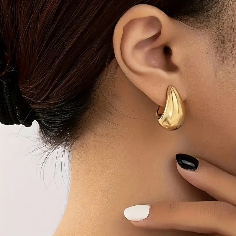 Gold Teardrop Hoop Earrings worn by a person with a neutral background