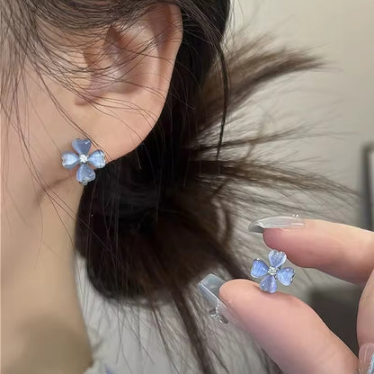 Close-up of a person wearing a Blue Flower Petal Hoop Earring with a hand holding another similar earring.