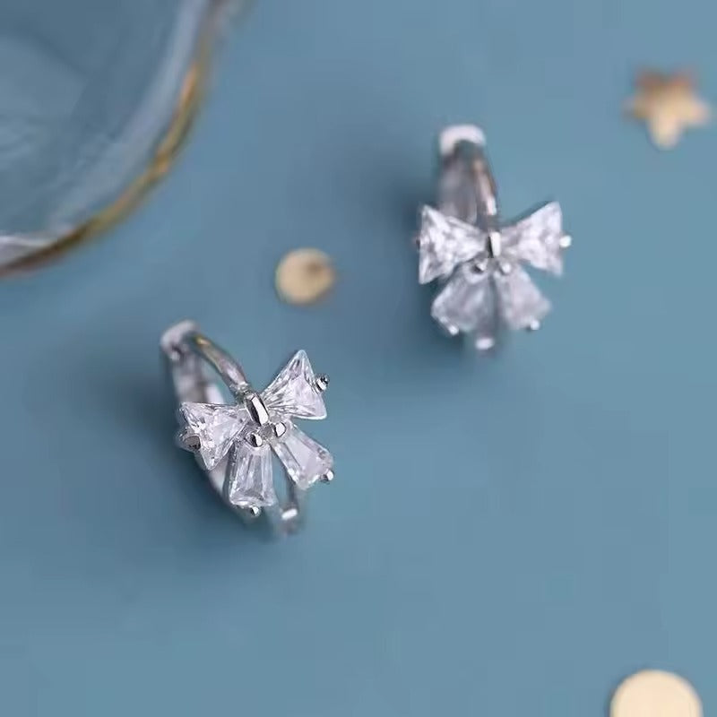 Tiny Crystal Ribbon Earrings on a blue background
