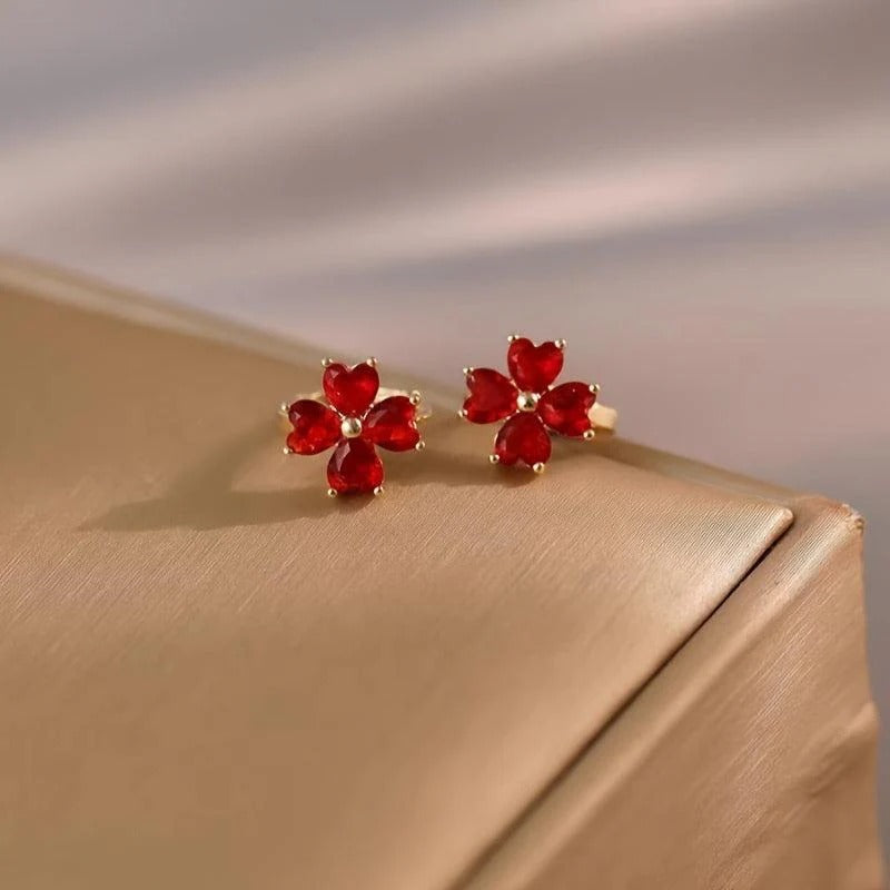 Ruby Red Flower Petal Hoop Earrings on a gold surface with a neutral background