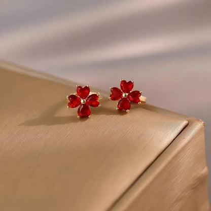 Ruby Red Flower Petal Hoop Earrings on a gold surface with a neutral background