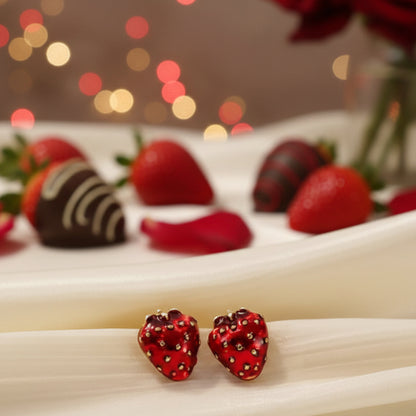 Ruby Red Strawberry Earrings on a beige fabric background