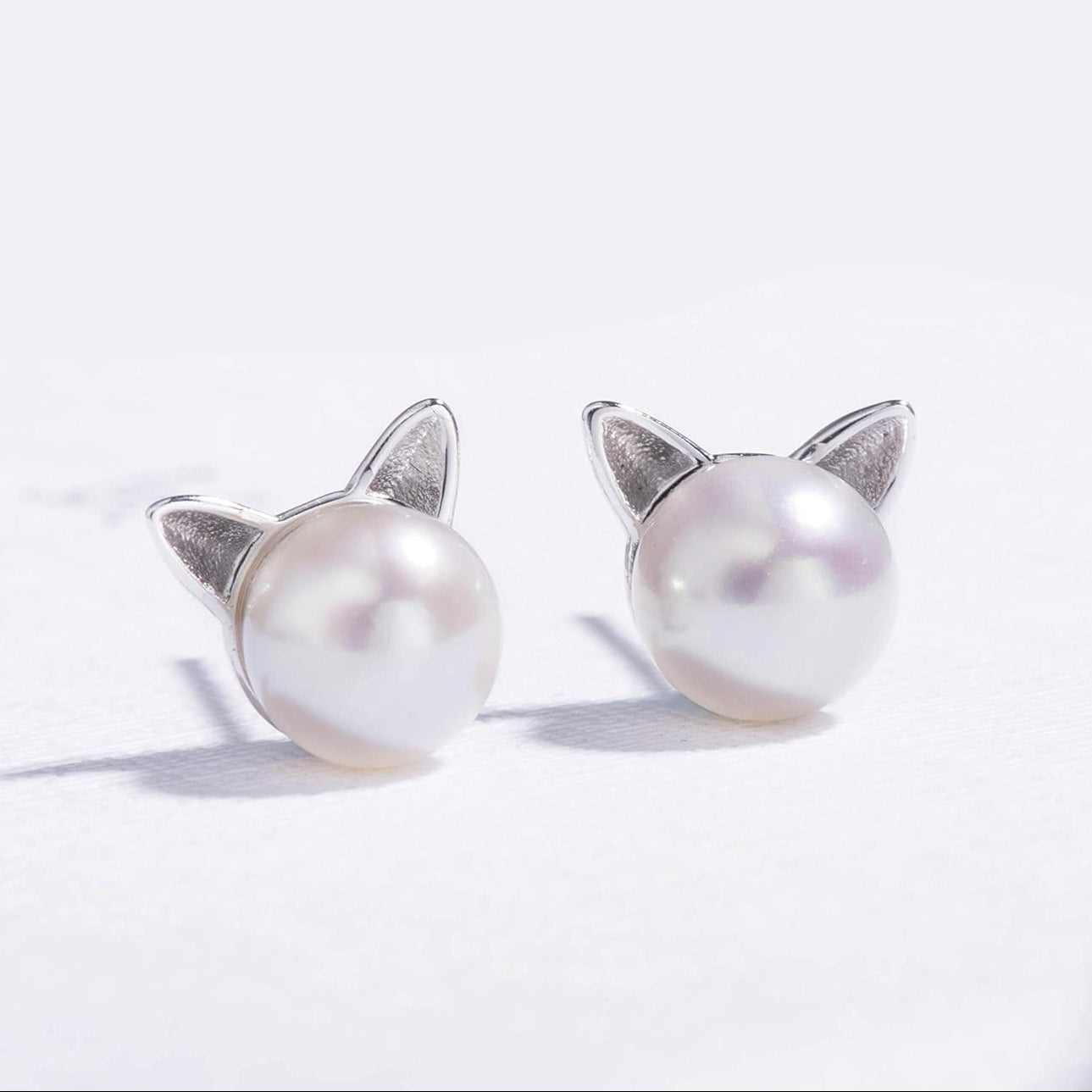 Pearl Cat earrings with cat ear designs on a white background