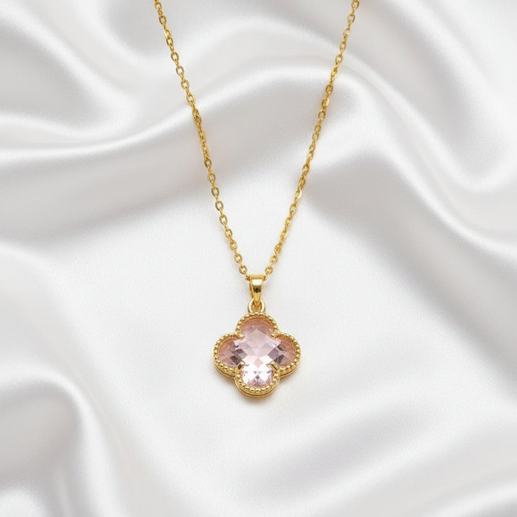Pink Clover Gold Necklace with a pink clover-shaped pendant on a white satin background