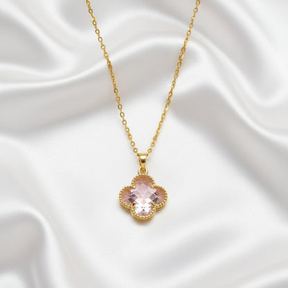 Pink Clover Gold Necklace with a pink clover-shaped pendant on a white satin background
