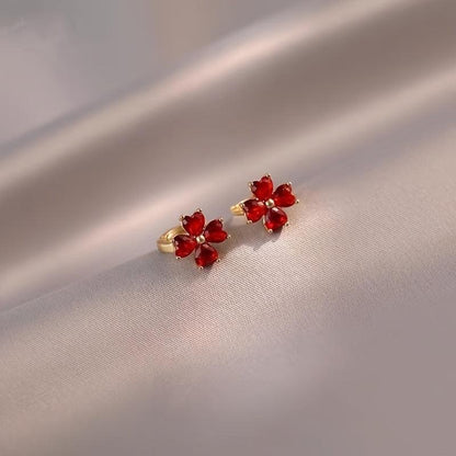 Pair of Ruby Red Flower Petal Hoop Earrings on a beige fabric background