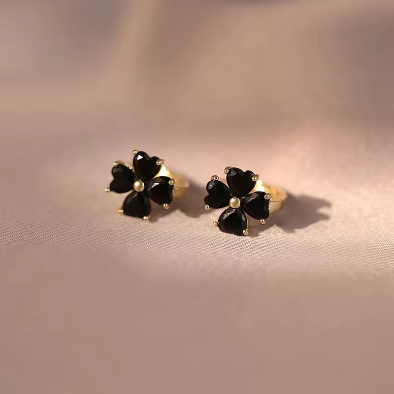 Black Flower Petal Hoop Earrings with gold accents on a soft pink background