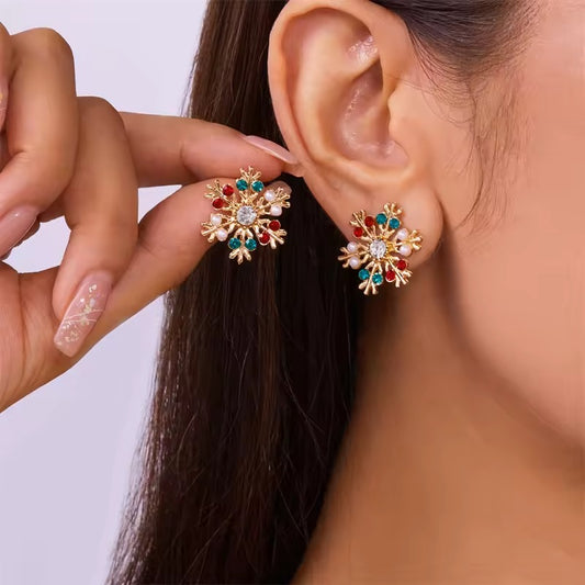 Close-up of a woman wearing Gold Gemstone Snowflake Earrings, held by a hand.