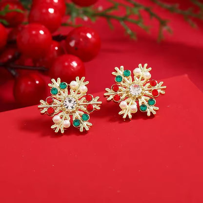 Gold Gemstone Snowflake Earrings with red and green accents on a red background