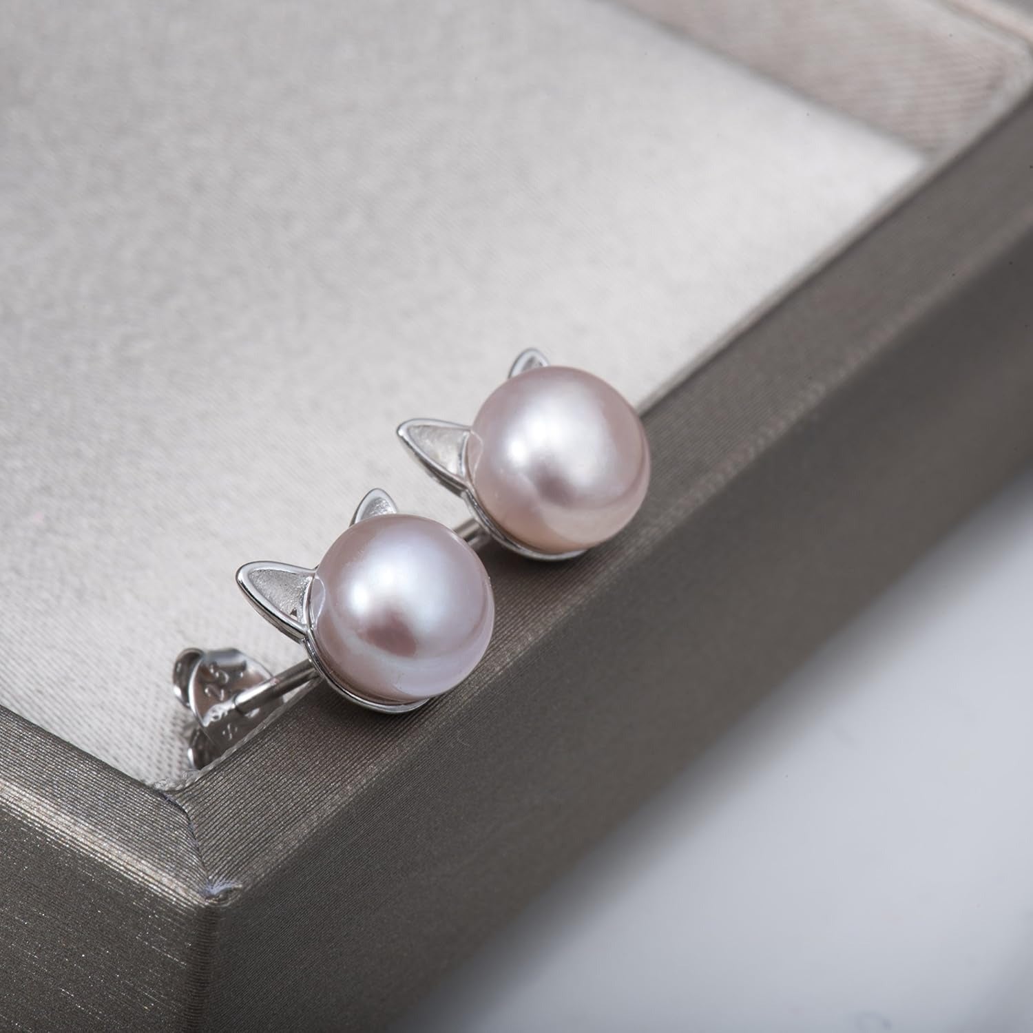 Pearl cat earrings with cat ear design on a gray surface