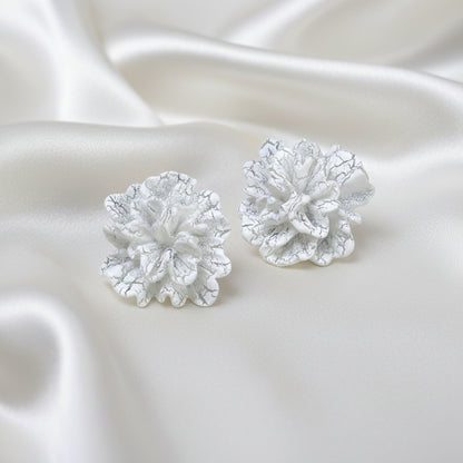 White Bloom Statement Stud Earrings on a white satin background