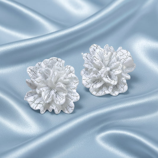 White Bloom Statement Stud Earrings on a silver satin background