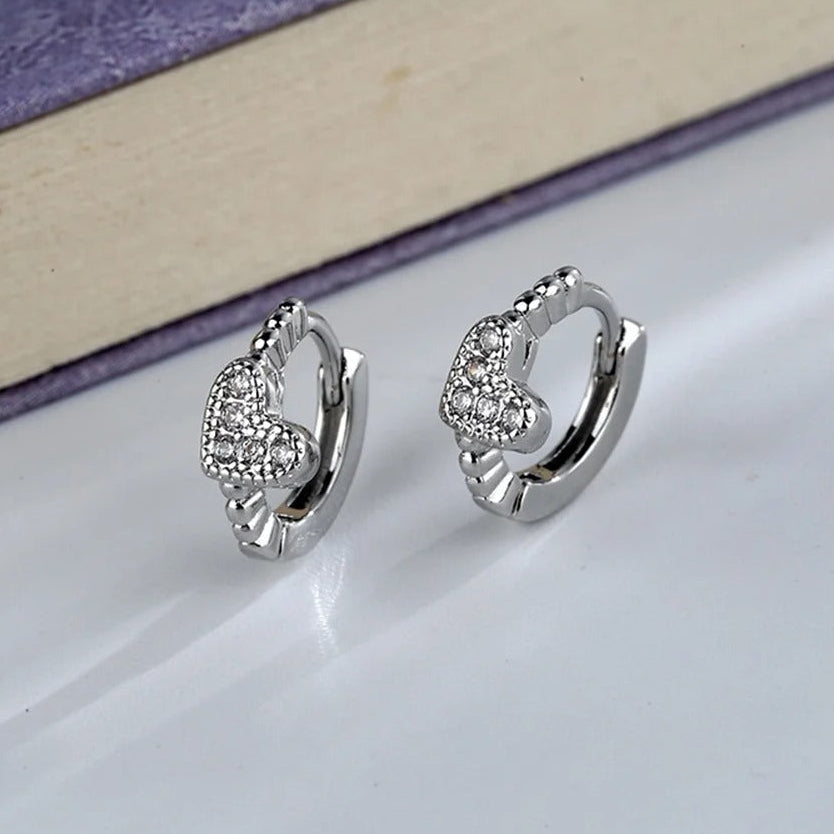Silver Tiny Crystal Heart Earrings with heart designs on a light surface