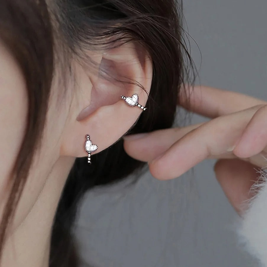 Close-up of an ear wearing a Silver Tiny Crystal Heart Earrings with a blurred background