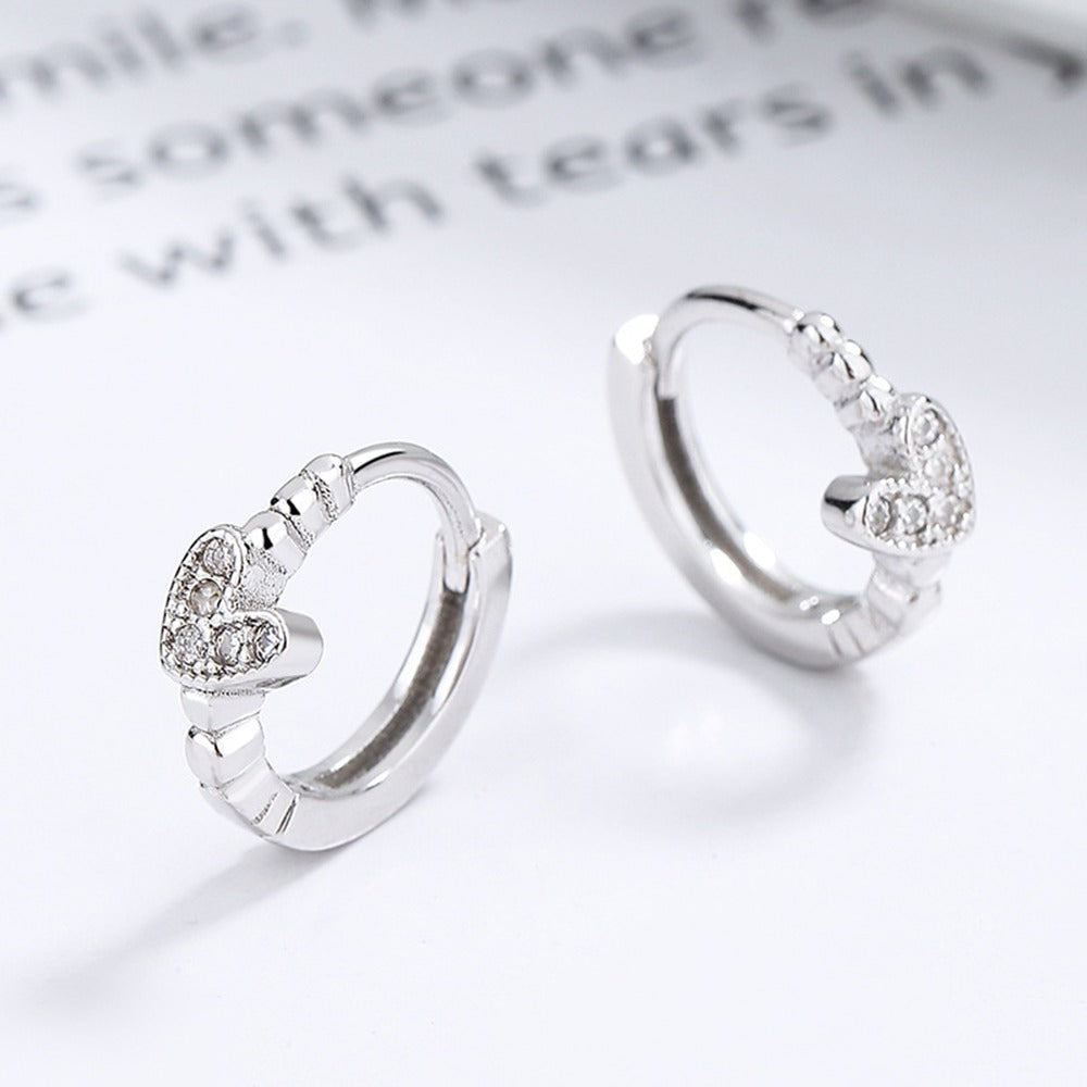 Silver Tiny Crystal Heart Earrings with heart-shaped designs on a light background