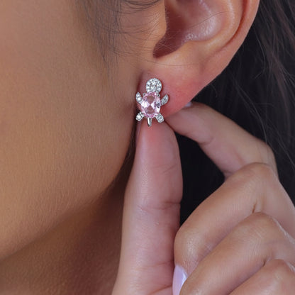 Close-up of an ear wearing a turquoise gemstone earring with a hand adjusting it.