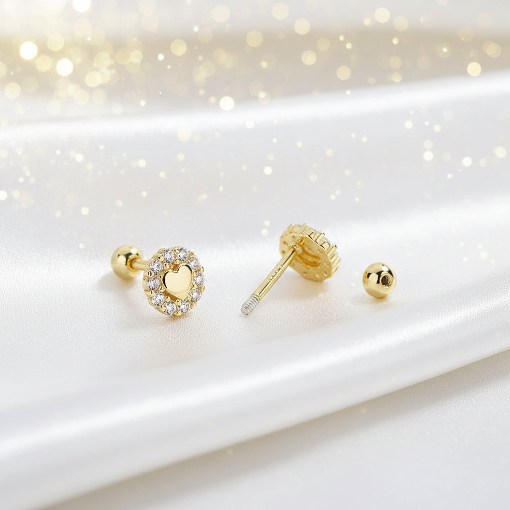 Tiny Gold Heart Halo Earrings on a white surface with a soft, blurred background
