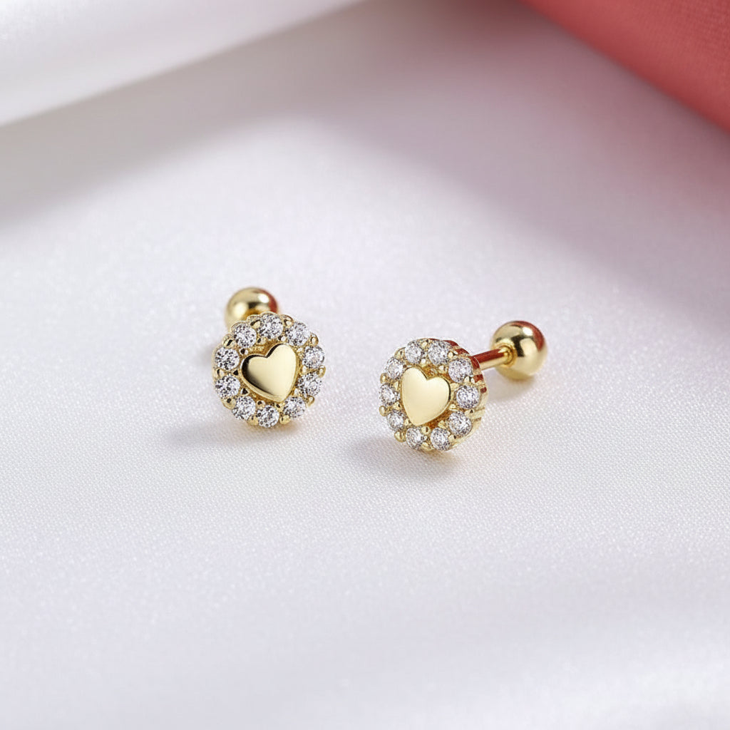Tiny Gold Heart Halo Earrings with clear stones on a light pink background