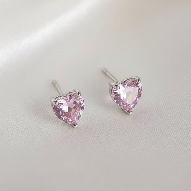 Heart-shaped pink gemstone earrings on a light gray background