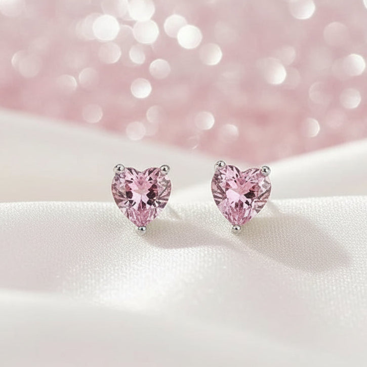 Heart-shaped pink earrings on a beige fabric background