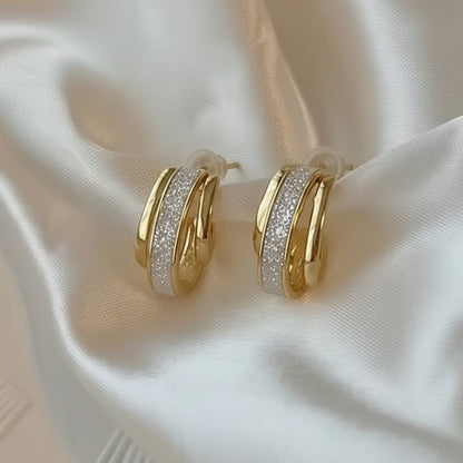 Gold Dust White & Gold Huggie Earrings on a soft white fabric background