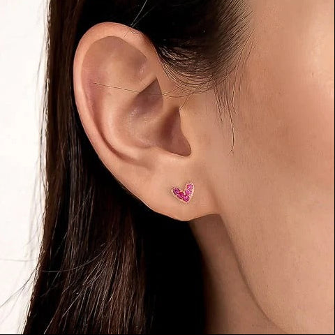 Close-up of an ear wearing a Petite Pink Zircon Heart Earrings with a blurred background