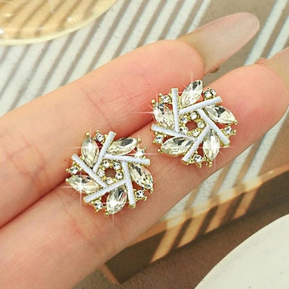 Golden Crystal Snowburst Earrings held on a hand with a neutral background