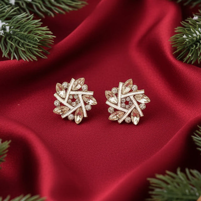 Golden Crystal Snowburst Earrings on a red fabric background with Christmas decorations.