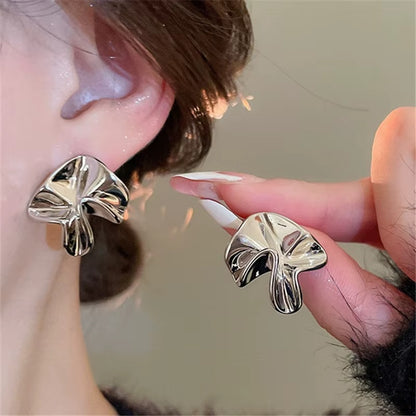 Gold Sculpted Petal Earrings being worn and held by a hand.