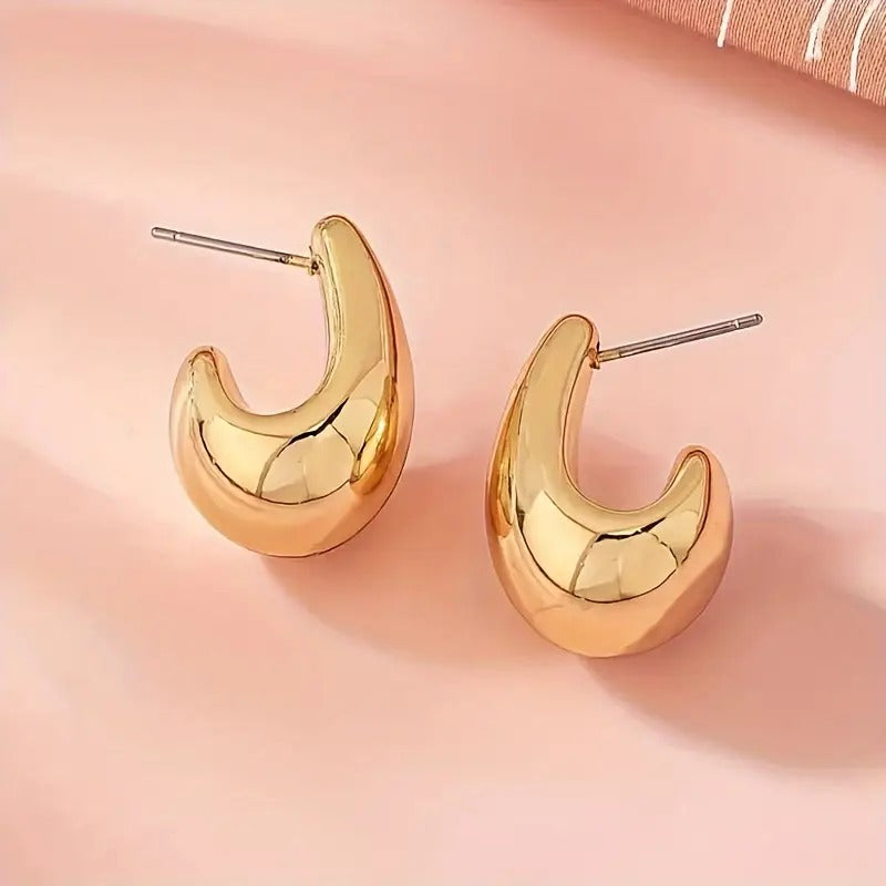 Gold Teardrop Hoop Earrings on a pink background