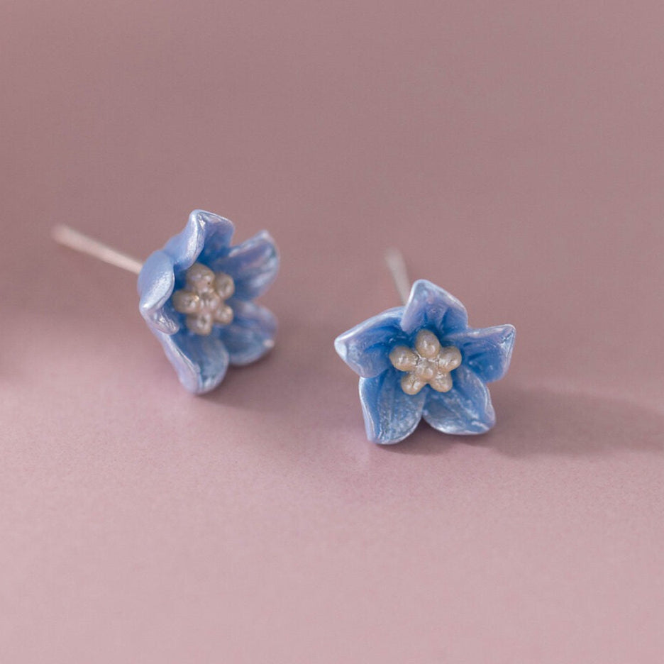 Pair of Blue Petal Blossom Earrings on a pink background