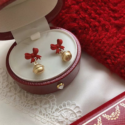 Jingle Bell Bow Earrings in a jewelry box on a red fabric background