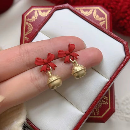 Jingle Bell Bow Earrings held by a hand against a red jewelry box.