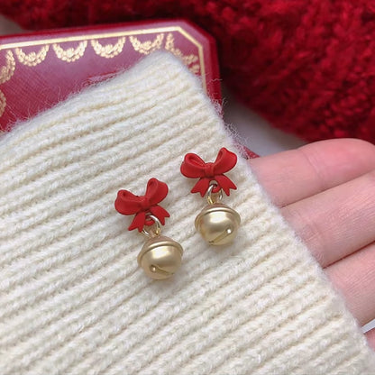 Jingle Bell Bow Earrings held by a hand on a textured surface