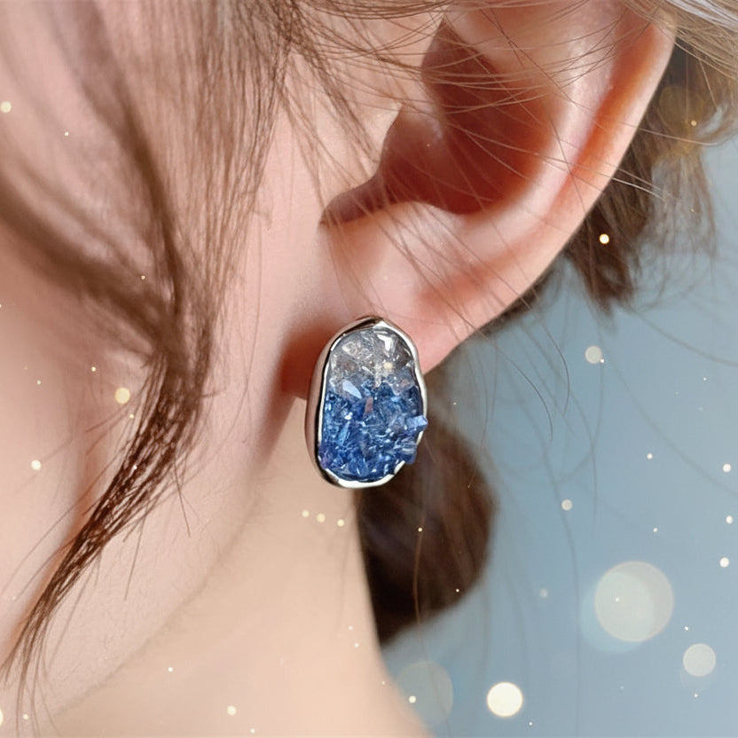 Close-up of an ear wearing a Glacier Blue Crystal Earring with a soft focus background