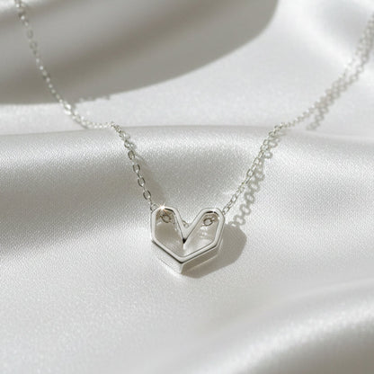 Silver necklace with a heart-shaped pendant on a gray background