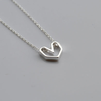Silver heart-shaped pendant necklace on a gray background